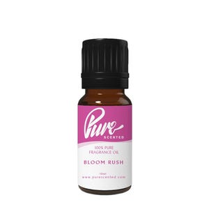 May include: A small amber glass bottle with a black cap. The label is pink and white, with the word "Pure" in a cursive font. The text "Bloom Rush" is below, and the bottle contains 10ml of fragrance oil.