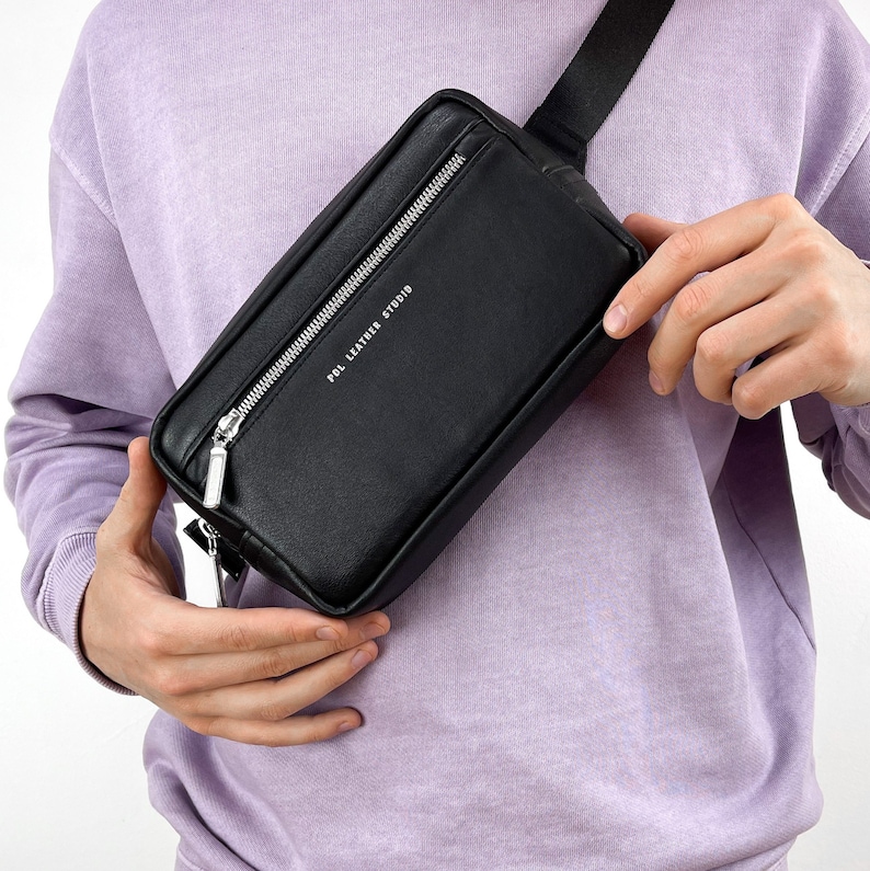 May include: Black leather fanny pack with a silver zipper and the text "POL LEATHER STUDIO" printed on the front.