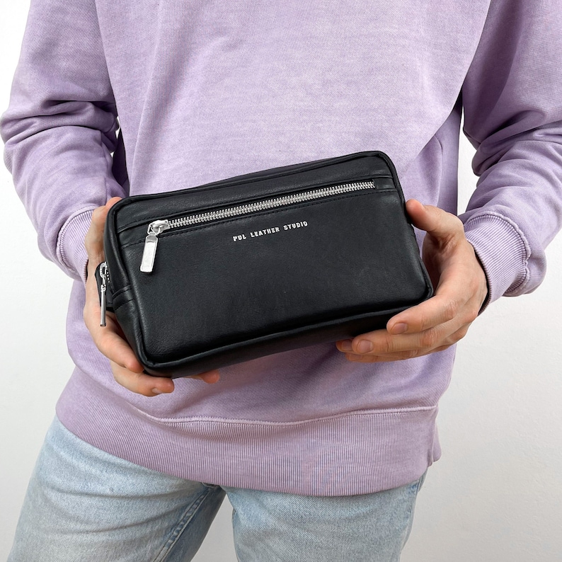 May include: A black leather zipped pouch with a silver zipper and the text "PDL LEATHER STUDIO" printed on the front.