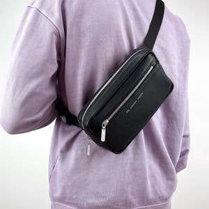 May include: A black leather fanny pack with a silver zipper and the text "POL LEATHER STUDIO" printed on the front.