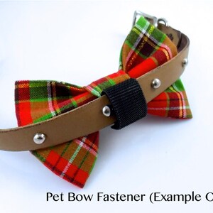 May include: A pet collar featuring a red, green, and gold plaid fabric bow attached to a tan strap with silver-toned metal studs. A black hook-and-loop fastener secures the bow to the collar. The text Pet Bow Fastener (Example Only) is visible.