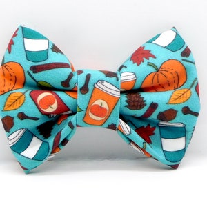 May include: A turquoise blue bow tie with a fall-themed print featuring pumpkins, leaves, coffee cups, and cinnamon sticks.