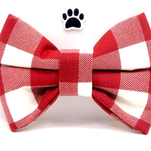 Puede incluir: Pajarita de cuadros rojos y blancos para una mascota. La pajarita está hecha de tela y tiene una forma de lazo clásica.