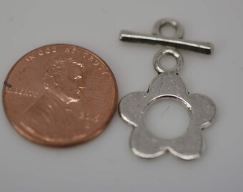 May include: Silver-toned metal flower toggle clasp with a bar and loop. The clasp is about the size of a US penny.