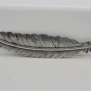 May include: A silver-toned feather bookmark with a detailed, textured design.
