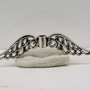 May include: Silver angel wing charm with a hole in the center for attaching to jewelry or other crafts.