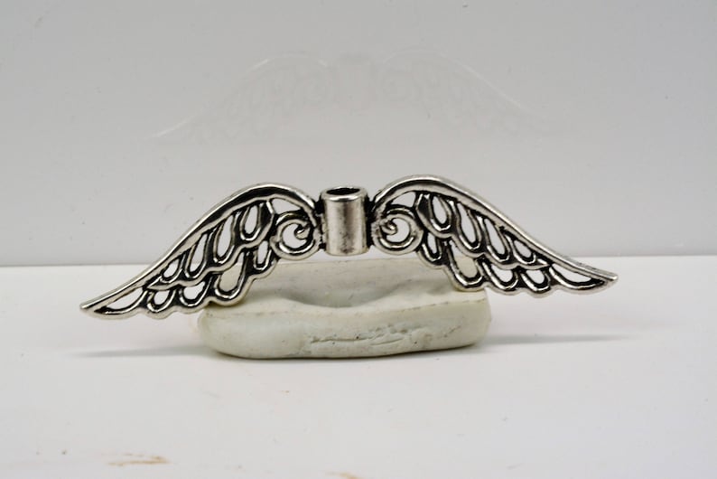 May include: Silver angel wing charm with a hole in the center for attaching to jewelry or other crafts.