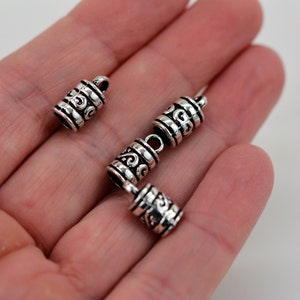 May include: Four silver metal end caps with a decorative swirl design. The end caps are approximately 1 inch long.