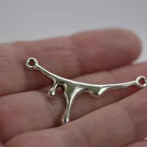 Puede incluir: Encanto de metal plateado con forma de l&iacute;quido que gotea, con dos bucles para sujetarlo a joyas u otras manualidades.
