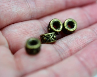May include: Four antique gold-toned metal beads with intricate designs. The beads are round and have a hole in the center. They are perfect for jewelry making or other craft projects.