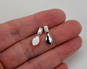 May include: Two small, silver-colored jewelry bails. One bail has a textured, dotted surface on the teardrop-shaped base, while the other has a smooth, polished surface. Both have a small loop at the top for attaching to a chain or other jewelry component.