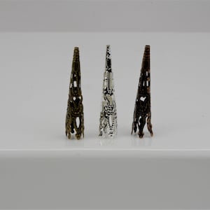 May include: Three decorative metal cones in different finishes: gold, silver, and bronze. Each cone has an intricate, lacy design.