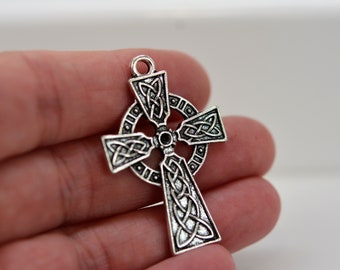 May include: Silver Celtic cross pendant with intricate knotwork design. The cross is detailed with a circle around the center and has a loop at the top for hanging.