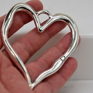 May include: Silver heart-shaped charm with a small heart engraved on the bottom.