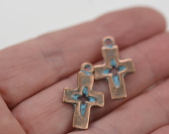 May include: Two antique copper-toned cross charms with a turquoise blue enamel design. The crosses have a cutout design in the center.