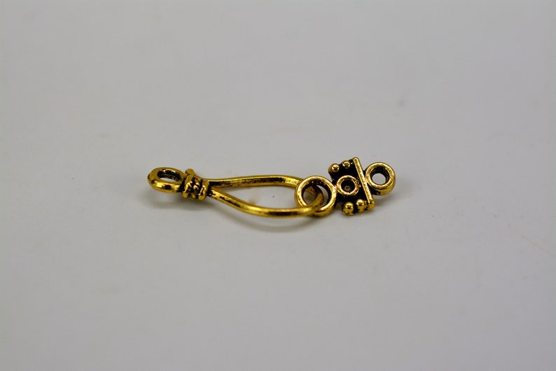 Peut inclure: Fermoir en m&eacute;tal dor&eacute; avec un motif d&eacute;coratif. Le fermoir a une boucle &agrave; une extr&eacute;mit&eacute; et une pi&egrave;ce d&eacute;corative &agrave; l'autre extr&eacute;mit&eacute;.