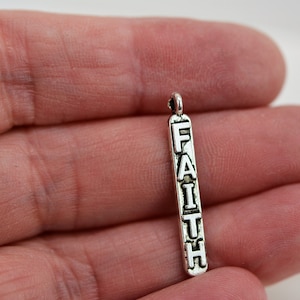 May include: Silver charm with the word "FAITH" spelled vertically.