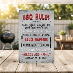 May include: A rectangular metal sign with the words "BBQ RULES" in red. The sign has a distressed, weathered look and includes phrases like "Come Hungry" and "Friends and Family - Always Welcome."