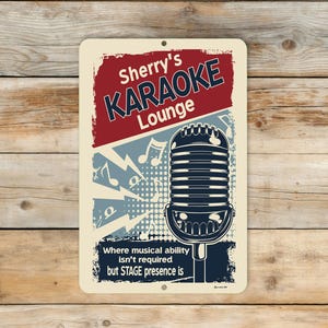 Personalized Karaoke Lounge aluminum wall sign with custom name displayed against weathered light wood planks, featuring a vintage microphone and retro typography. Text on the sign reads, "Where musical ability isn't required but STAGE presence is."
