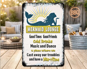 May include: A rectangular metal sign with a distressed finish. The sign features a mermaid silhouette, the words "MERMAID LOUNGE", and phrases like "Good Times, Good Friends, Cold Drinks, Music and Dance". The sign is on a wooden surface.