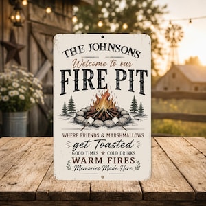 May include: A rectangular metal sign with the text "THE JOHNSONS Welcome to our FIRE PIT" in a rustic font. The sign features a campfire illustration with marshmallows, trees, and the phrases "get Toasted", "Good Times", and "Memories Made Here".