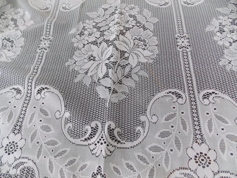May include: White lace fabric with a floral pattern. The lace has a delicate, intricate design with small flowers and leaves.