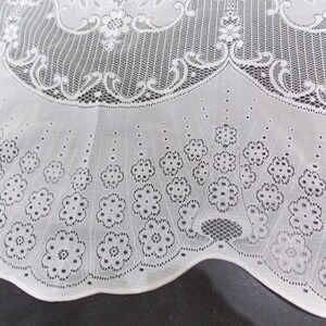 May include: White lace tablecloth with a scalloped edge and a floral pattern. The lace is delicate and intricate, with small flowers and leaves.