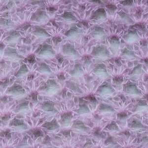 May include: Close-up of a soft, pink, fuzzy knit fabric with a delicate, openwork pattern.