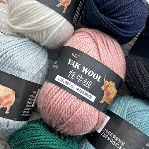 May include: Assortment of yarn skeins in various colors, including white, light blue, pink, dark blue, black, and green. The yarn is labeled "YAK WOOL 牦牛绒" with the text "以匠心暖人心, 来自高原的爱" in Chinese characters.
