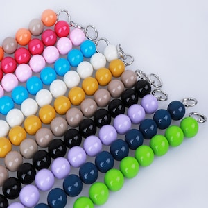 May include: A set of colorful wooden beads strung on wire, arranged in rows of increasing size. The beads are in shades of red, pink, blue, white, yellow, brown, black, purple, green, and blue.