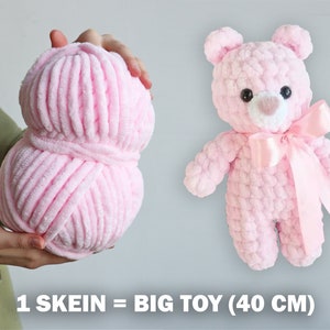 K&ouml;nnte beinhalten: Eine Kn&auml;uel rosa Garn, ausreichend f&uuml;r einen 40 cm gro&szlig;en Pl&uuml;schteddyb&auml;r. Der Text "1 SKEIN = BIG TOY (40 CM)" ist unter dem Garn sichtbar.