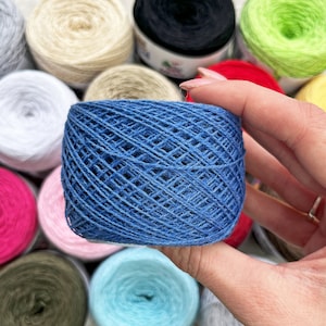 May include: A ball of blue yarn with a textured surface. The yarn is wound into a ball shape and is ready for knitting or crocheting.