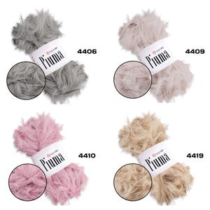 May include: Four skeins of YarnArt Piuma yarn in various colors: gray (4406), light beige (4409), pink (4410), and tan (4419). Each skein has a fluffy, feather-like texture and a label with the brand name and color number. Ideal for knitting and crochet projects.