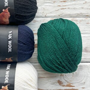 May include: Four balls of yarn in different colors: black, navy blue, white, and green. The yarn is labeled "Yak Wool".