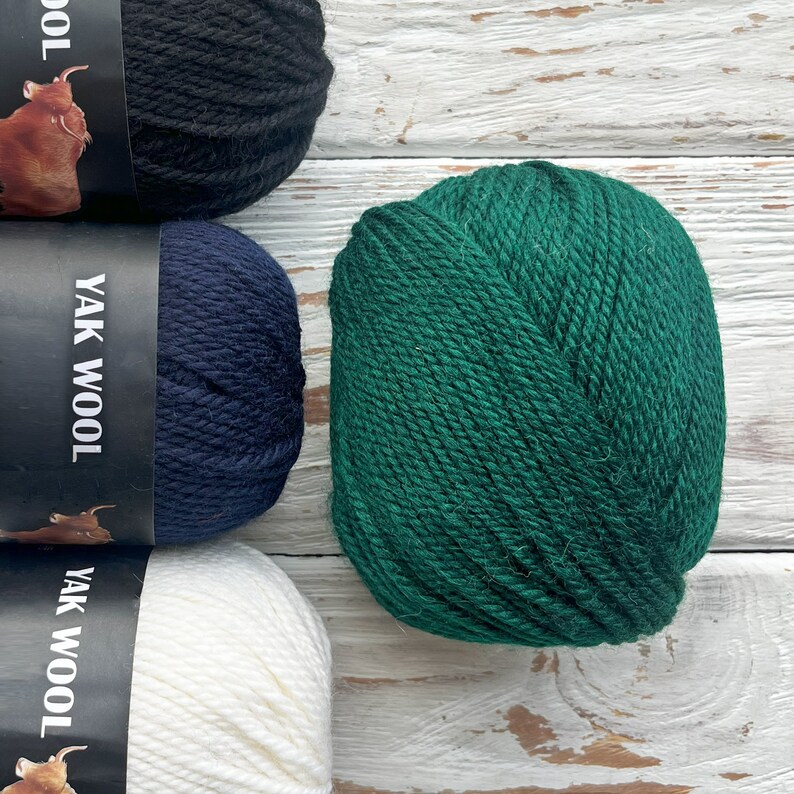 May include: Four balls of yarn in different colors: black, navy blue, white, and green. The yarn is labeled "Yak Wool".