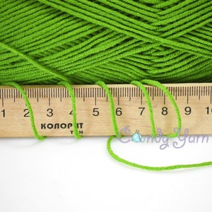 Puede incluir: Hilo verde brillante con una regla de madera que muestra medidas en cent&iacute;metros. El hilo es de color s&oacute;lido y la regla est&aacute; marcada con n&uacute;meros y texto. La imagen tambi&eacute;n incluye el texto "Candy Yarn".