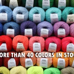 May include: A collection of yarn skeins in various colors, including blue, green, purple, red, and orange. Each skein has a label. The text "MORE THAN 40 COLORS IN STOCK" is displayed across the bottom of the image.