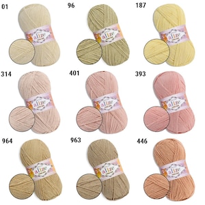 Puede incluir: Una colecci&oacute;n de ovillos de hilo Alize Cotton Gold en varios colores, incluyendo beige, verde, amarillo, rosa y marr&oacute;n. Cada ovillo est&aacute; etiquetado con un n&uacute;mero y una muestra de color, ideal para tejer y hacer ganchillo.