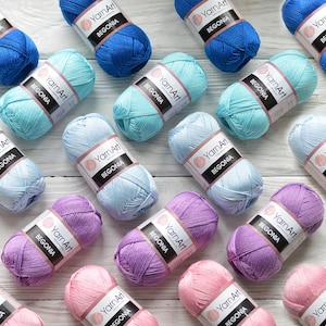 May include: Assortment of yarn balls in various colors, including light blue, pink, purple, and light blue. Each ball has a label that reads "YarnArt Begonia".