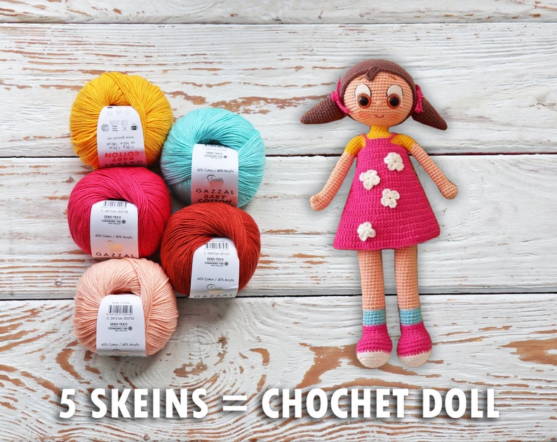 May include: A handmade crochet doll with a pink dress and white flower accents stands beside five skeins of colorful yarn. The yarn colors include yellow, teal, pink, red-orange, and peach. Text on the image reads "5 Skeins = Crochet Doll."