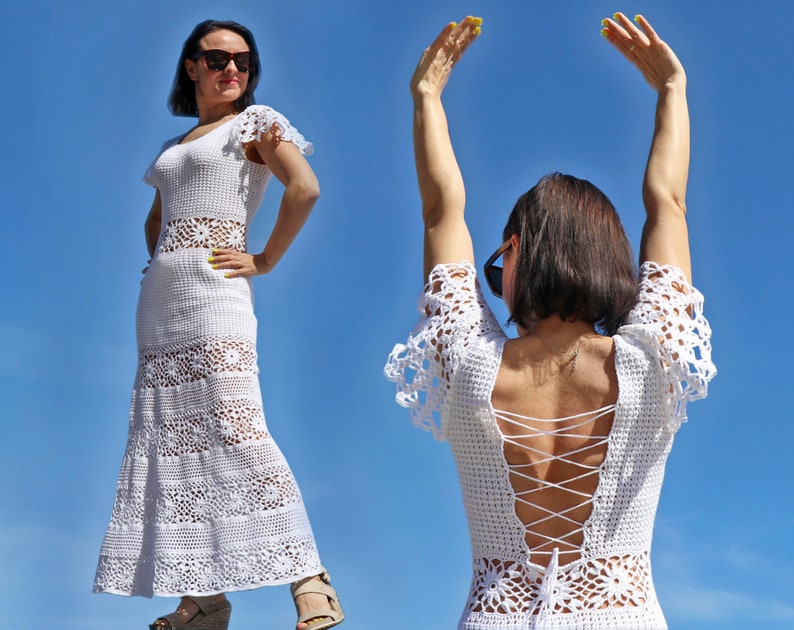 May include: A white crochet dress with a fitted bodice and a flared skirt. The dress features a floral pattern and short sleeves with a scalloped edge. The back of the dress has a lace-up design. The model is wearing sunglasses.