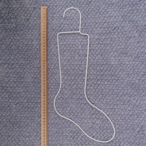 May include: White metal stocking hanger shaped like a sock. The hanger is approximately 47 inches long.