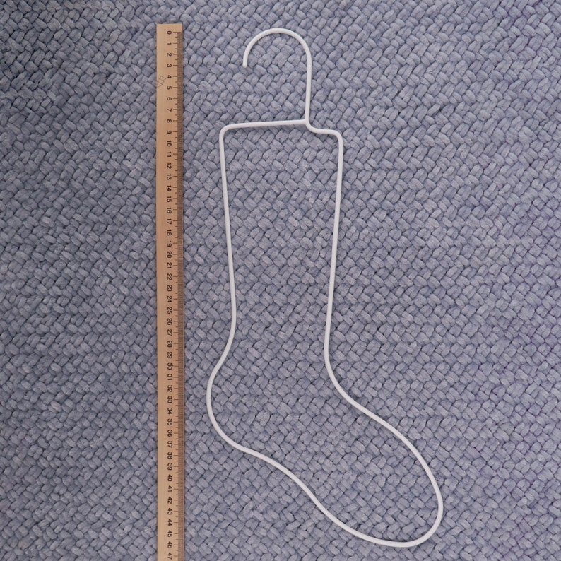 May include: White metal stocking hanger shaped like a sock. The hanger is approximately 47 inches long.