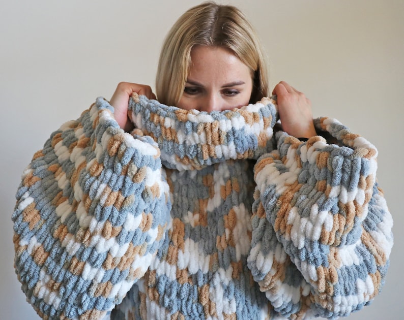 May include: An oversized sweater with a high neck, featuring blue, white and brown stripes.