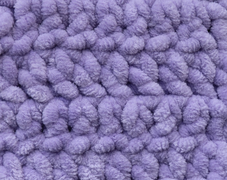 K&ouml;nnte beinhalten: Nahaufnahme eines weichen, violetten, flauschigen Stoffes mit einem strukturierten, gewebten Muster.