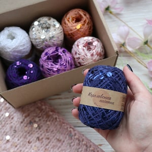 May include: A set of eight spools of yarn with sequins, in a cardboard box. The spools are in various colours, including white, silver, pink, purple, and blue. The yarn is labelled "Королевская пайетка" in Russian.