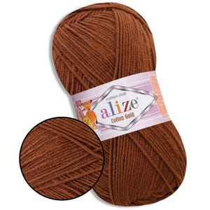Puede incluir: Ovillo de hilo Alize Cotton Gold marr&oacute;n. El hilo est&aacute; bien enrollado y tiene un aspecto texturizado. La etiqueta presenta el nombre de la marca y personajes de dibujos animados. Un primer plano muestra la textura detallada del hilo.