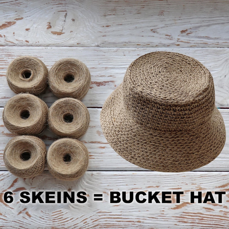 K&ouml;nnte beinhalten: Sechs Kn&auml;uel braunes Garn sind in zwei Reihen zu je drei angeordnet. Neben dem Garn befindet sich ein brauner geh&auml;kelter Bucket-Hut. Der Text "6 SKEINS = BUCKET HAT" ist unter dem Bild gedruckt.