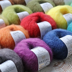 May include: A variety of colorful yarn skeins in shades of orange, green, red, purple, blue, and teal. The yarn is labeled "GAZZAL SUPER MOHAIR" and includes the composition: 22% Polyamide, 31% Superwash Merino Fine, 47% Super Kid Mohair.