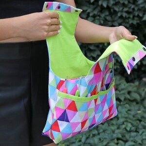May include: A colorful geometric fabric bag with a lime green lining and multiple pockets. The bag is open and has various knitting needles and tools inside.